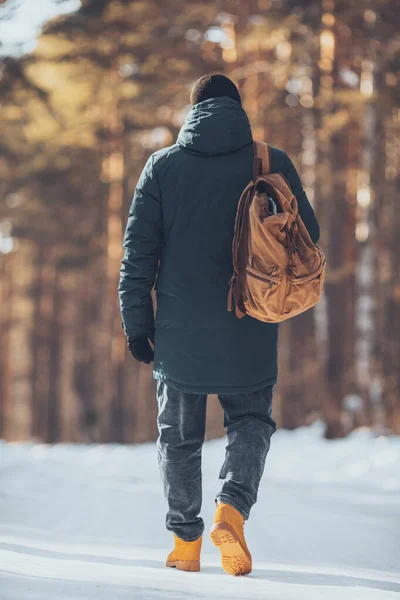 一个男人 背着旅游帆布背包 在冬天的森林里 穿着夹克和红色的远足靴 高质量的照片 免版税图库图片