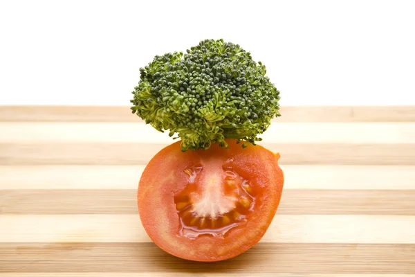 Röda tomater med gröna broccoli på träplatta — Stockfoto