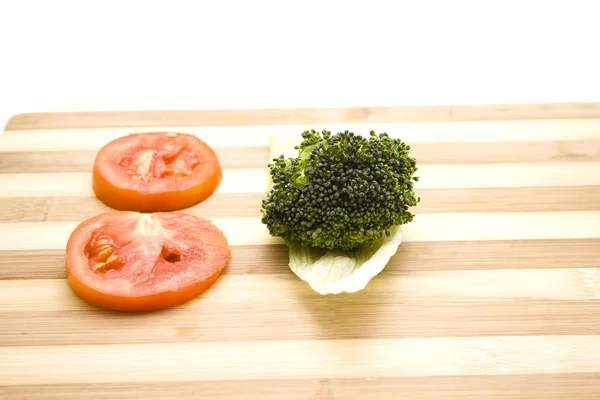 Broccoli med tomat på träplatta — Stockfoto