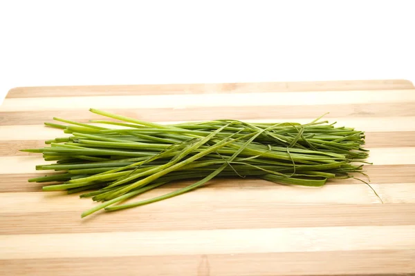 Chives verdes frescas en placa de madera —  Fotos de Stock