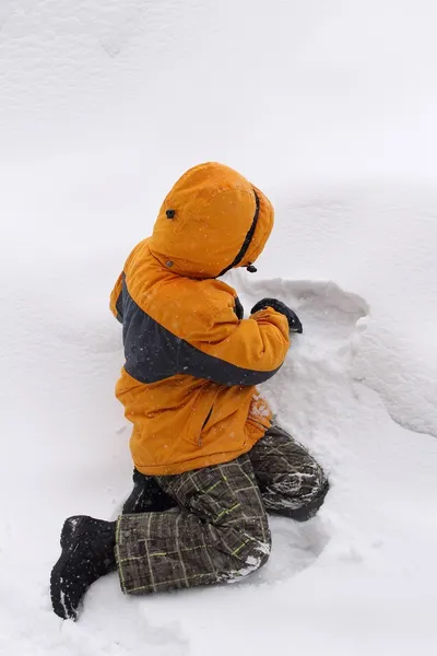 Junge spielt in einer Schneewehe — Stockfoto