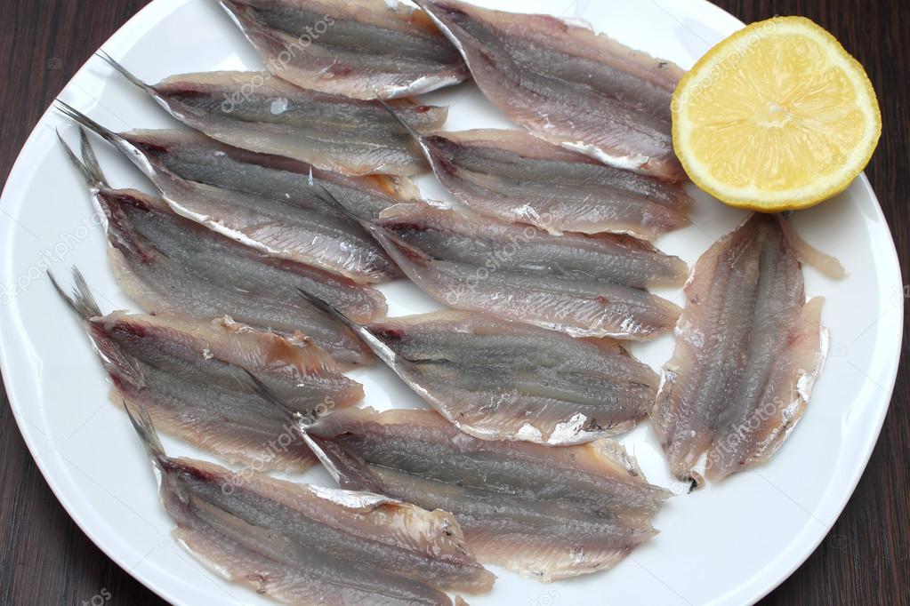 Raw anchovy fillets in glass baking dish in front of microwave oven