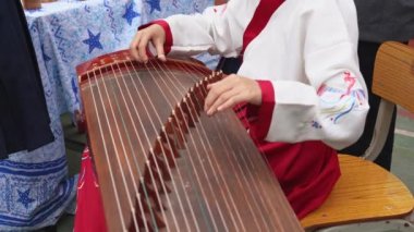 Geleneksel bir Çin müzik aleti olan Guzheng 'i küçük bir kız çalıyor.