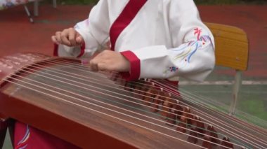 Geleneksel bir Çin müzik aleti olan Guzheng 'i küçük bir kız çalıyor.