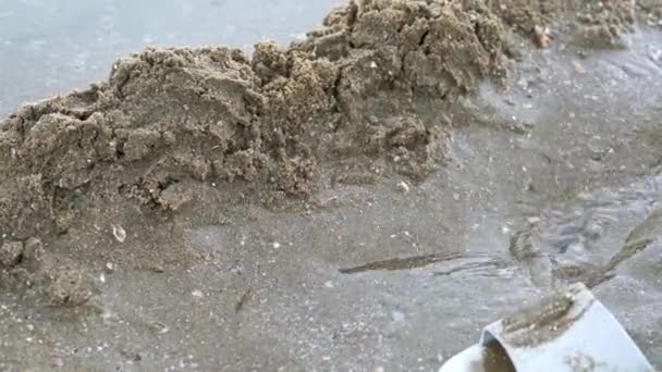 Ένας Άνθρωπος Χτίζει Σωρούς Άμμου Στην Παραλία Δίπλα Στη Θάλασσα — Αρχείο Βίντεο