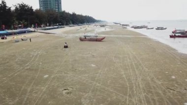 Sahilde plaj motosikleti, deniz kenarında spor yapan insanlar.