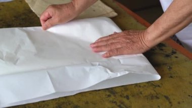 Eski bir kaligraf yazı yazmadan önce pirinç kağıdını katlamaya hazırlanır.