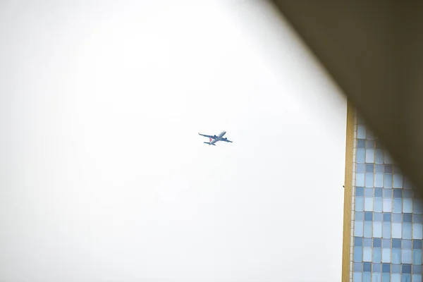 民間航空会社が市内の高層ビルの上を飛ぶ — ストック写真