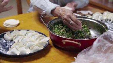 Çinli bir aile birlikte oturup hamur tatlısı yapıyor.