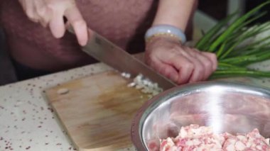 Bir şef, çörekleri pişirmek için ince doğranmış yeşil soğan doğruyor.