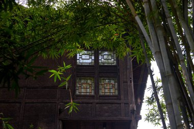 Partial closeup of an old wooden house in a Chinese bamboo forest clipart