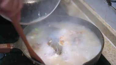 Bir şef balık kafası çorbası pişiriyor, balık kafası kızartıyor ve çorba yapmak için su ekliyor.