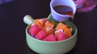 Füme somon ve sebze salatasına sos döken bir adam.