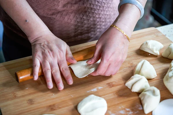 A chef in a Chinese kitchen is making bun skins with a rolling pin