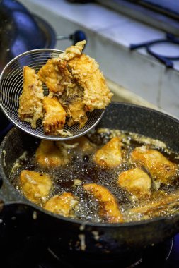 Çinli bir şef kızartma tavasında balık nugget kızartıyor.