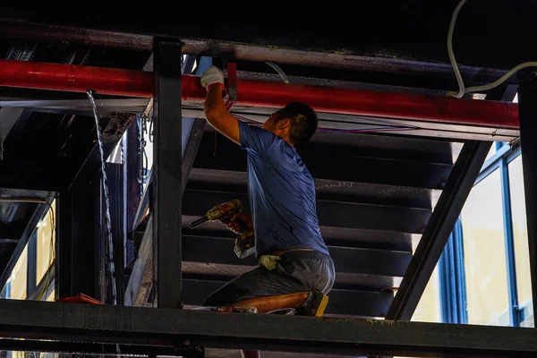 Back view of a worker in interior decoration doing ceiling works