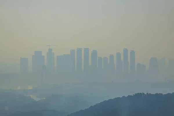 朝の濃霧の中で遠くに見える高層ビルのシルエット — ストック写真