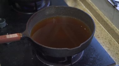 Mutfakta bir aşçı kızartma tavasında yumurta pişiriyor.