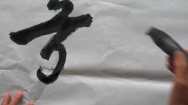 An old calligrapher is creating and writing Chinese calligraphy works. Translation: Chinese Traditional Tang Poems and Calligraphy Poems.