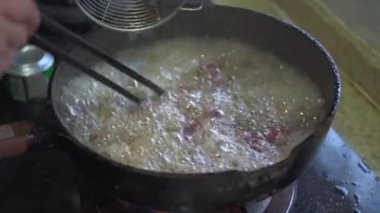 A chef is frying beef in a frying pan