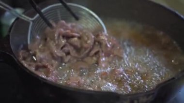 Bir şef kızartma tavasında biftek pişiriyor.