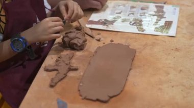A child is playing with clay, making a clay model
