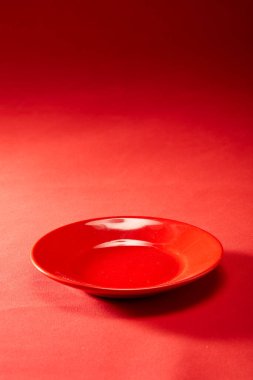 Kırmızı bir yemek tabağı kırmızı deri bir arka plan bezinin altında yatıyor.