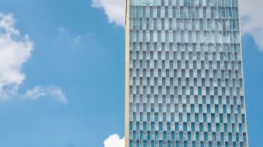 Partial blue sky and white clouds of high-rise buildings with glass curtain walls in sunny summer