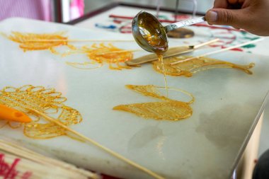 Bir zanaatkar geleneksel Çin yemekleri yapıyor, şekerli resimler yapıyor.