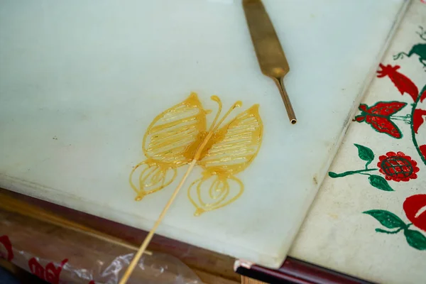 A craftsman is making traditional Chinese snacks, painting sugar paintings