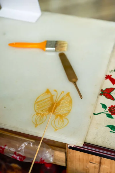 A craftsman is making traditional Chinese snacks, painting sugar paintings