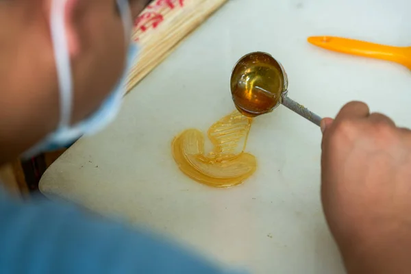 A craftsman is making traditional Chinese snacks, painting sugar paintings