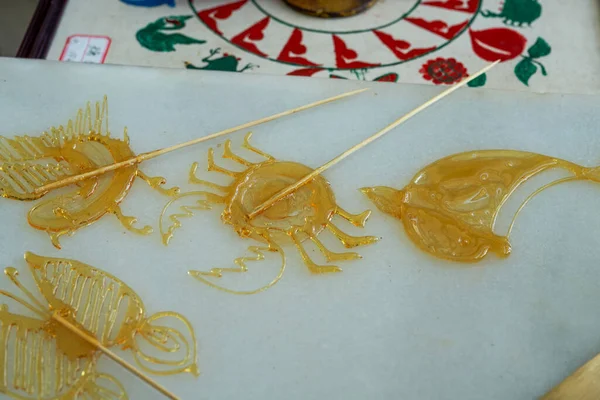 A craftsman is making traditional Chinese snacks, painting sugar paintings