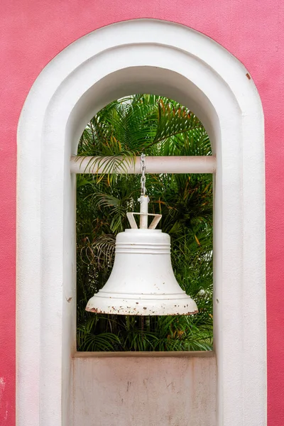 A white ringing bell in a pink garden