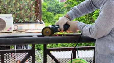 A worker is using a cutting machine to cut an iron guardrail to escalate in slow motion