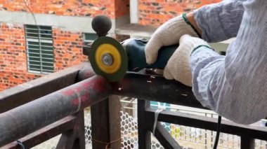 A worker is using a cutting machine to cut an iron guardrail to escalate in slow motion