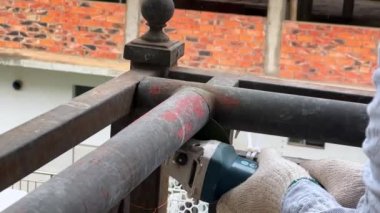 A worker is using a cutting machine to cut an iron guardrail to escalate in slow motion