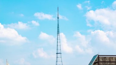 Time-lapse video of blue sky and white clouds with TV signal tower in the city