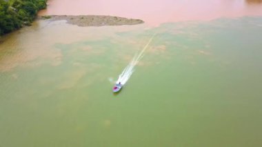 A person drives a speedboat across the confluence of the two rivers, the two-color river