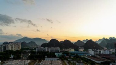 Guilin, Guangxi, Çin 'deki şehir binaları ve dağlarla sabahın erken saatlerinde güneş doğuyor.