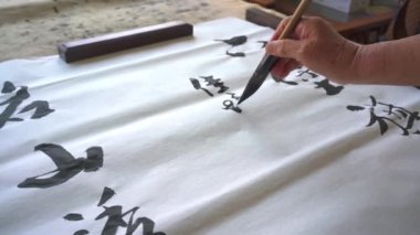 Eski bir kaligraf yazı karakterleri yazıp, yazı işleri yaratıyor. Çevirisi: Mükemmel bir ortam, çay içmek neşe katabilir.
