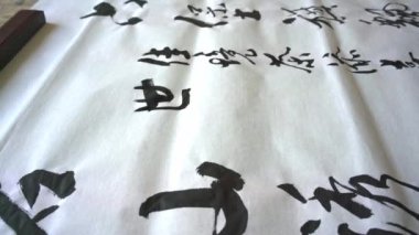 Eski bir kaligraf yazı karakterleri yazıp, yazı işleri yaratıyor. Çevirisi: Mükemmel bir ortam, çay içmek neşe katabilir.