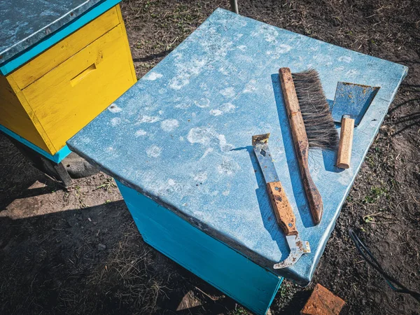 Sarı ve mavi renkli bir arı kovanının çatısındaki eski aletler.