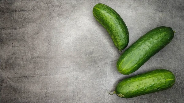 Three fresh green cucumbers on gray marble background. — Stock Photo, Image