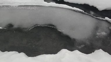 Nehir kışın eriyen karın altında akar..