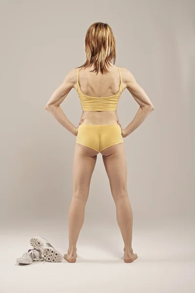 Muskulöse junge Frau im gelben Kleid — Stockfoto