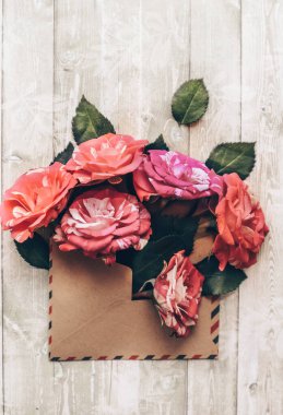 roses in an envelope on a light wooden background