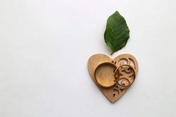 wooden heart and gold wedding rings on a white background