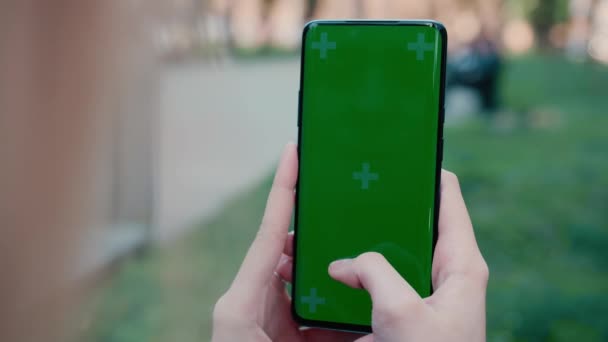Lviv, Ukraine - May 6, 2022: Close up of a womans hand scrolling a mobile telephone with a vertical green screen in car chroma key smartphone technology cell phone street touch message display hand — Stock video
