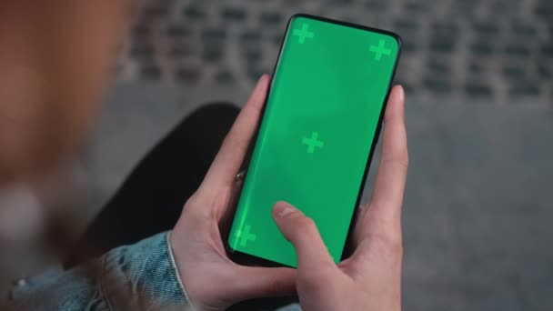 Lviv, Ukraine - May 6, 2022: Close up of a womans hand scrolling a mobile telephone with a vertical green screen in car chroma key smartphone technology cell phone street touch message display hand — Stock video